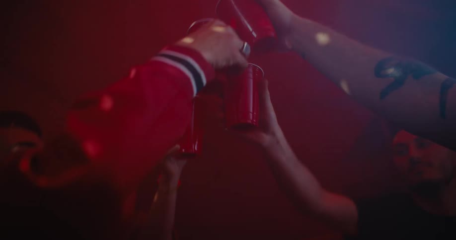 Men at a nightclub put their glasses together and high five one another