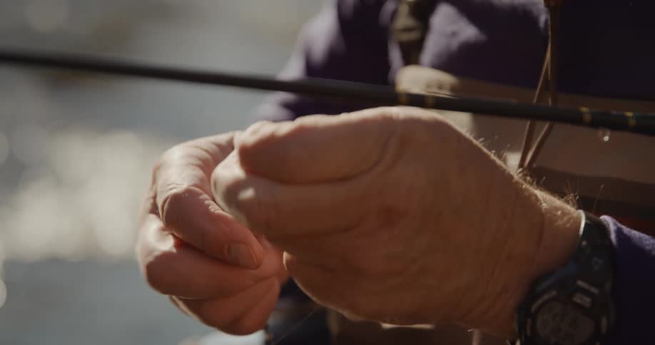 A man is tying bait to his fishing pole