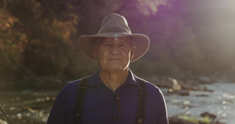 An elderly man in front of a river