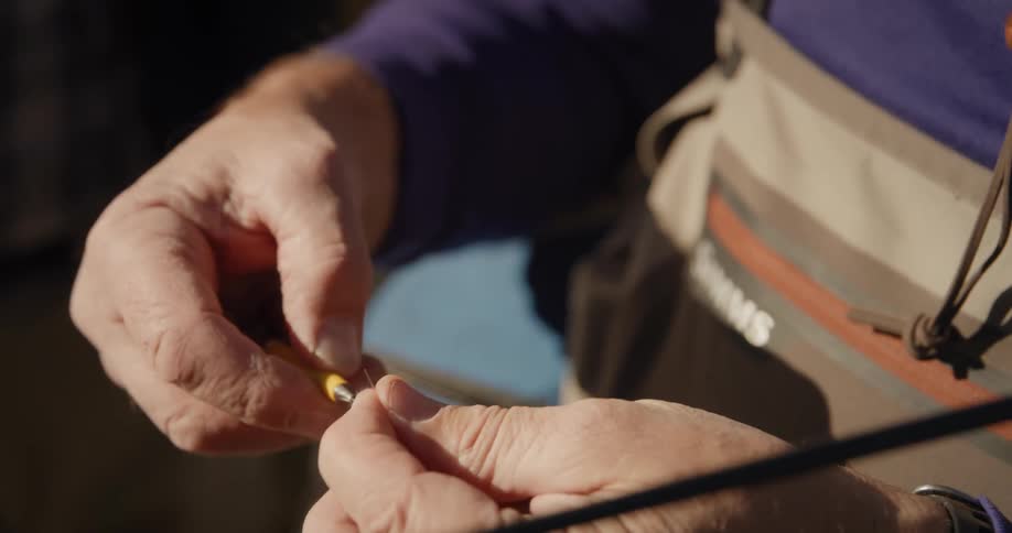 A fisherman attaches bait to fishing wire