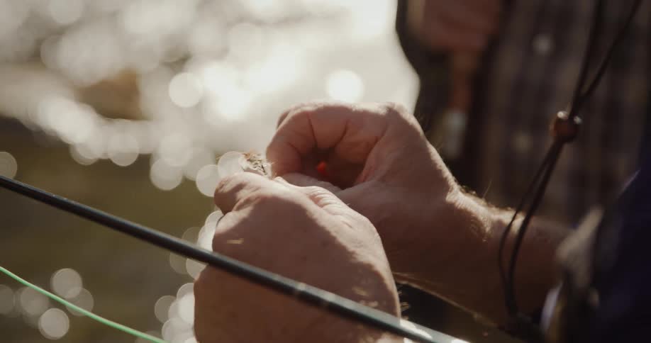 A man is choosing a hook for his fishing pole
