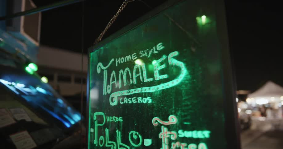 A light flashes on a sign on a street with vendors tents along the walkway