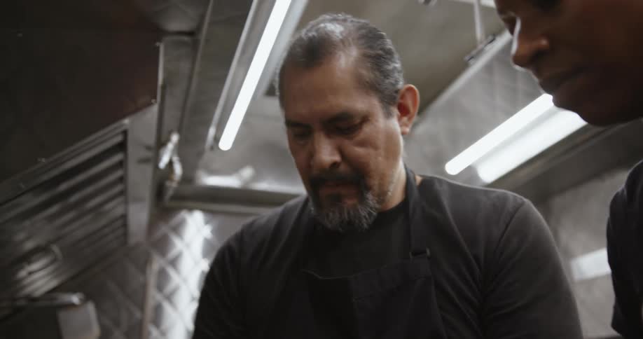 Two men are standing in a restaurant kitchen cooking