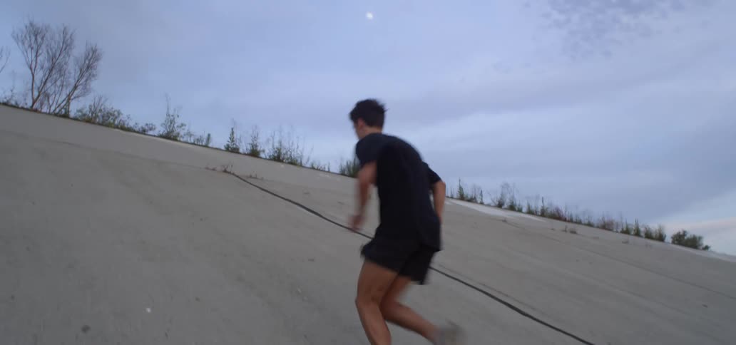 Man runs ups sloping concrete side of large storm drain system