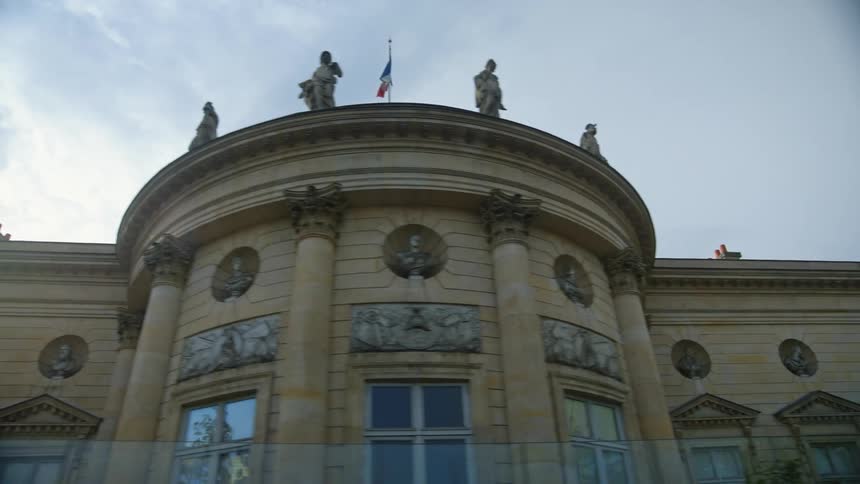 Statues on the roof of an european building at morning seen from a moving vehicle