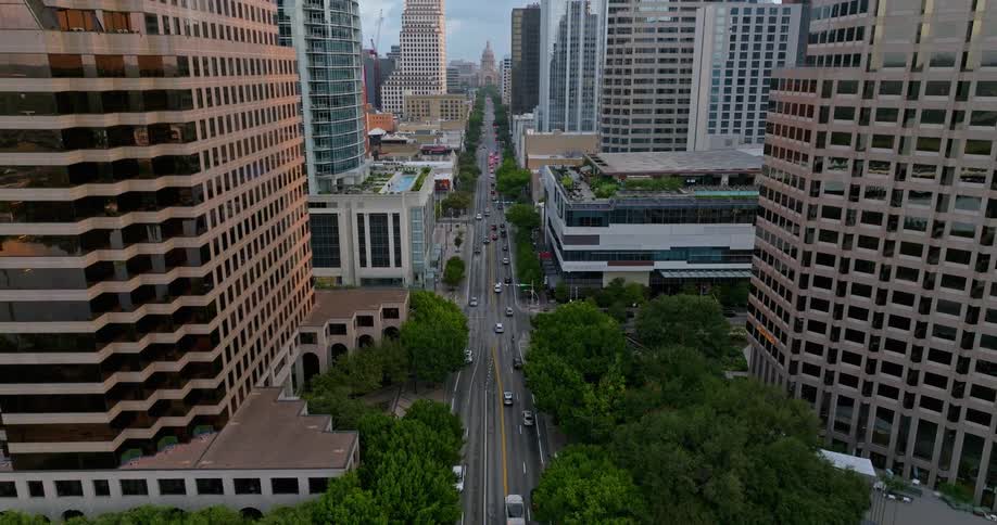 Aerial view of light traffic on a long avenue through the city at mornin