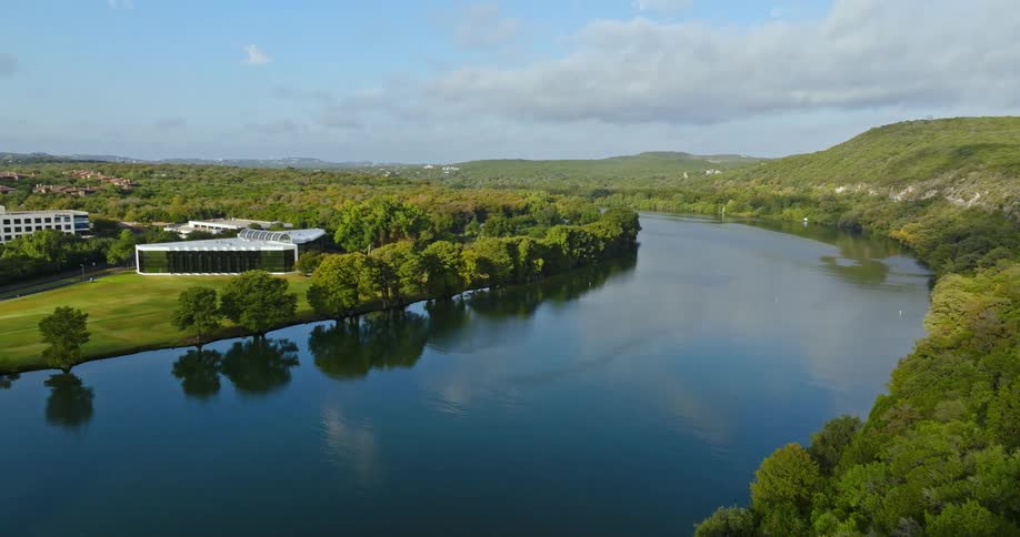 A curve in a river near a group of large buildings in the countryside during the day