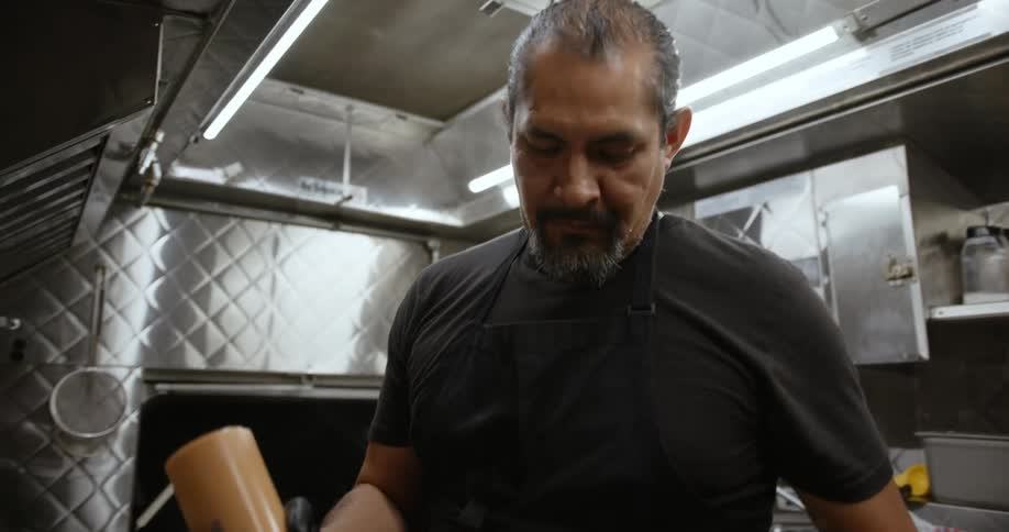 A man in a restaurant shake sauce as he cooks