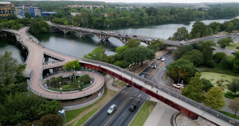 Traffic moves on a road along the coast and bridges across the lake traveling in and out of town