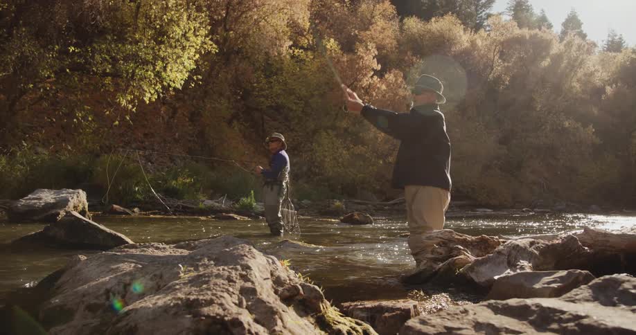A pair of men fish while standing in a river on an autumn day