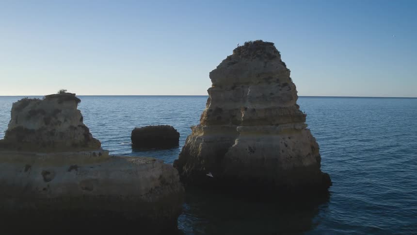 Large rock formations in the ocean near a mountainous coast line