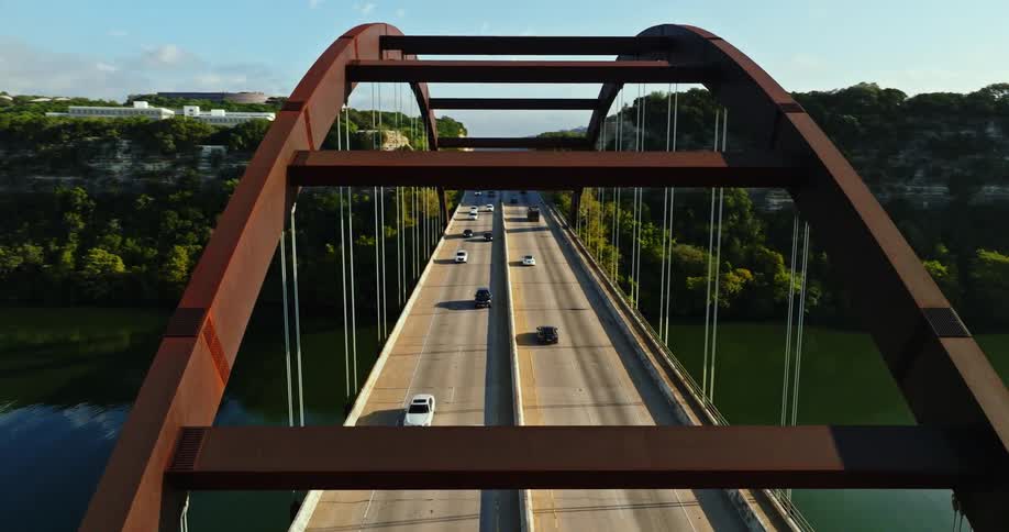 Aerial view of traffic over an arched bridge over a river at morning