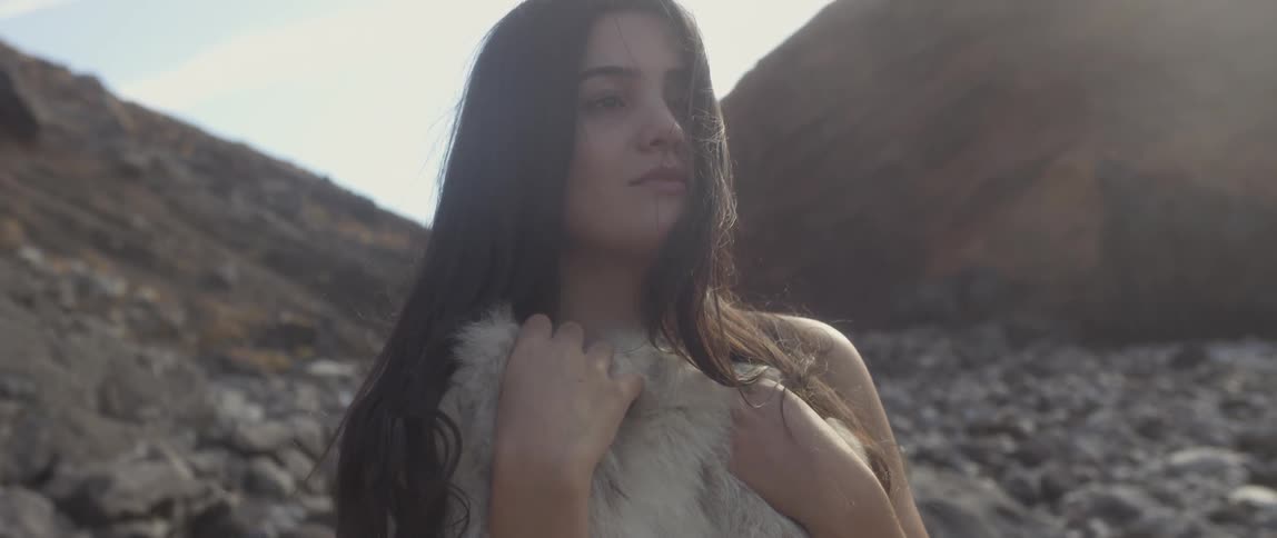 Woman holding a pelt to her chest at the beach