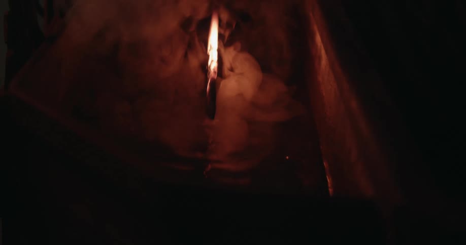 A man dips a burning knife into a vat of liquid