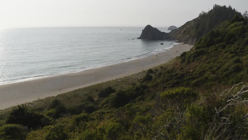 Slow push towards an empty and secluded beach surrounded by cliffs and hills
