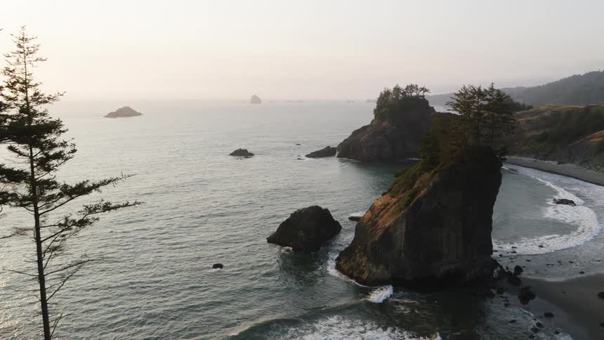 Gentle ocean waves wash ashore a beach surrounded by sea cliffs and large rock formations