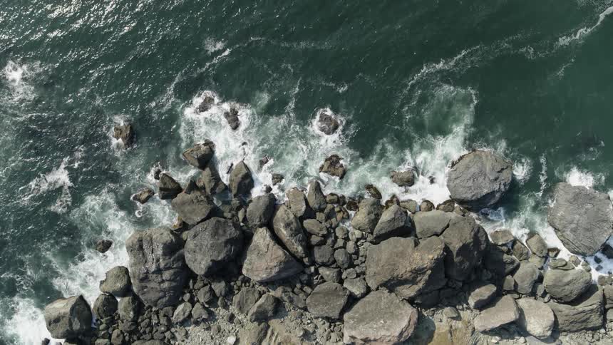 Waves create frothy whitewater as they crash against rocks along the shoreline