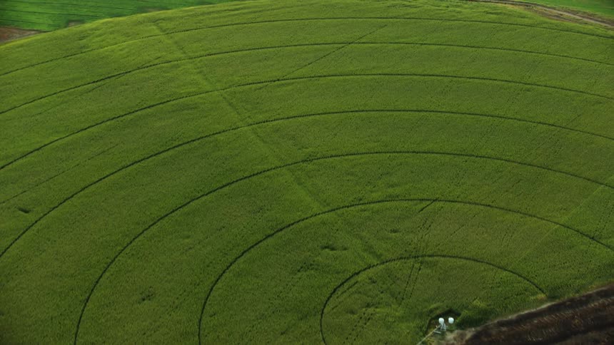 A semi circle arched pattern is carved into a field in this high energy aerial shot from an airplane