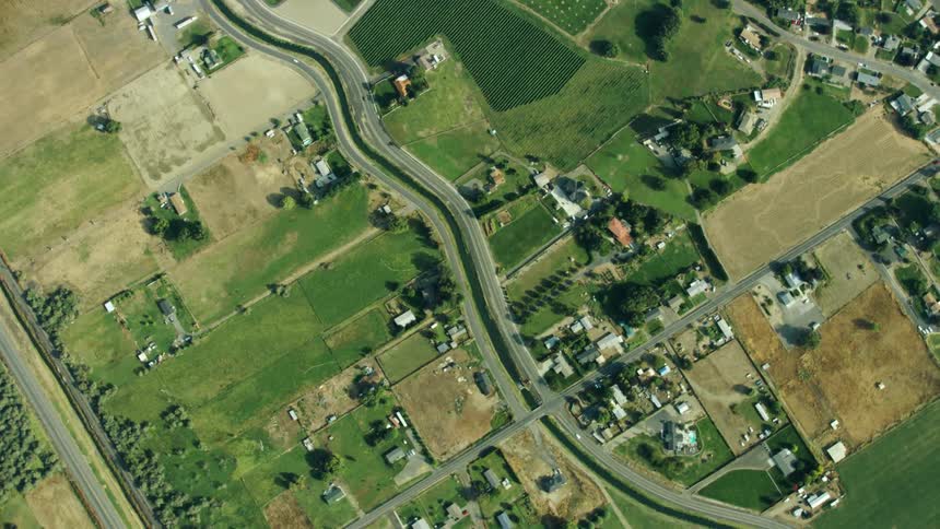Looking straight down in this high altitude aerial shot of an irrigation canal weaving through agricultural land and suburban neighborhoods