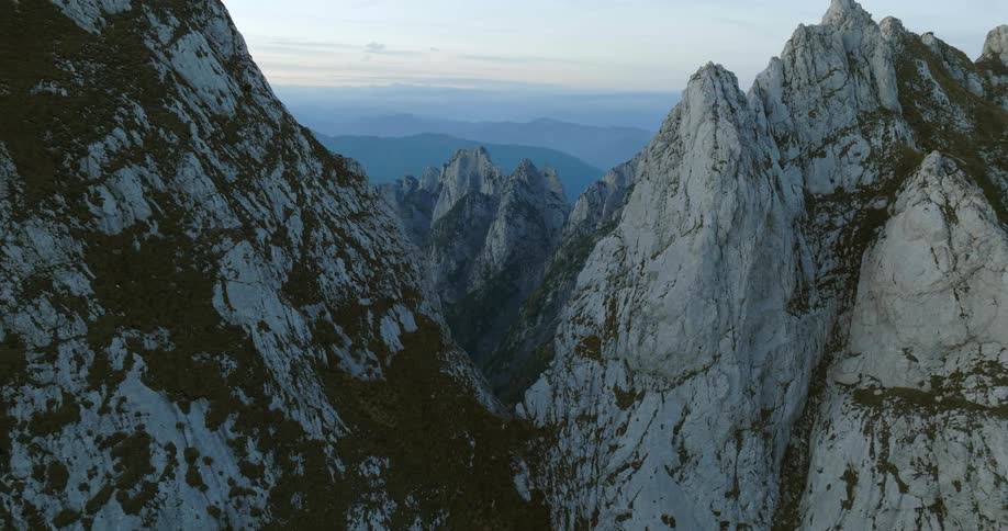Snow covered peaks rise sharply into the sky above lower mountains