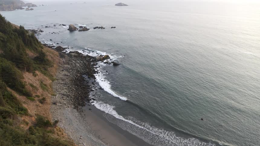 Steep descent along a tree covered sea cliff towards a rocky beach