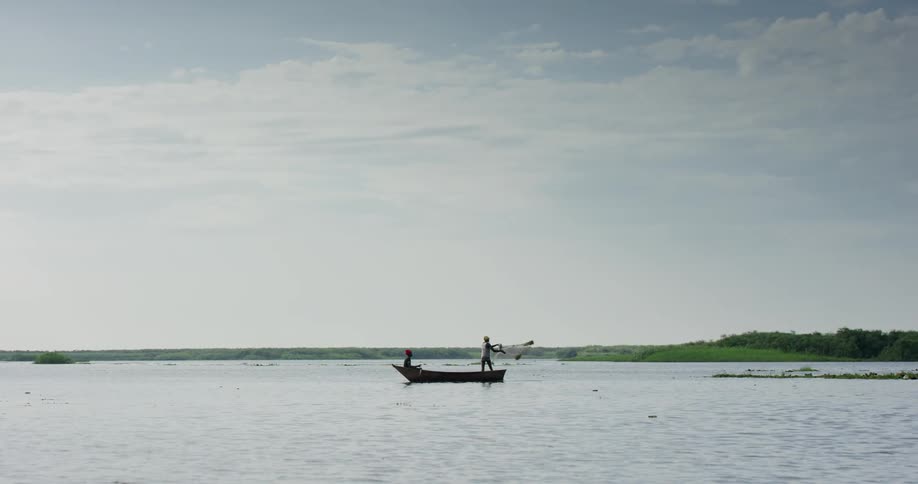 Fisherman cast a net on boat floating on water