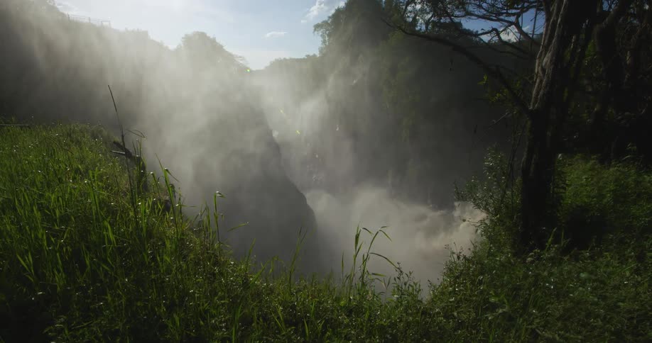 A canyon shrouded in mist due to a waterfall during the day