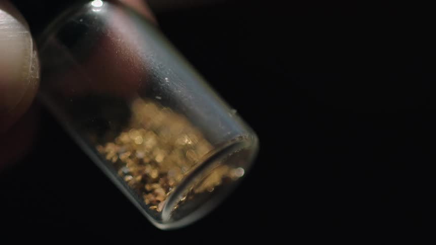 A person examines a small vial containing a powdery substance