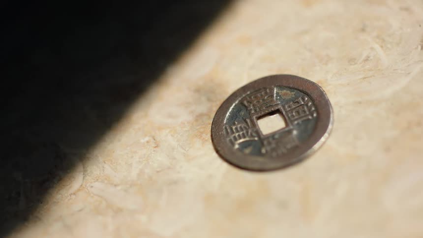 A small metal coin has a square shaped opening in the middle of it