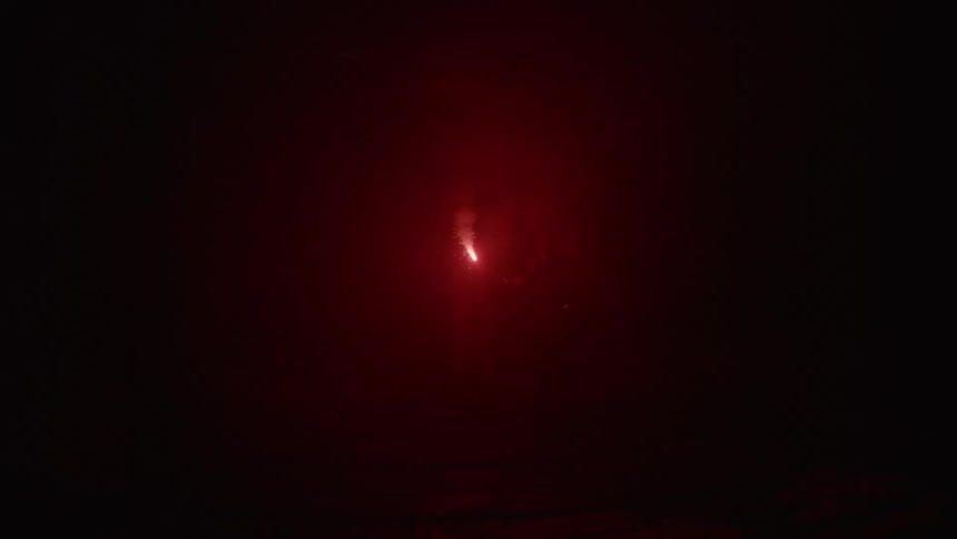 A single flare is burning in the darkness before it is extinguished