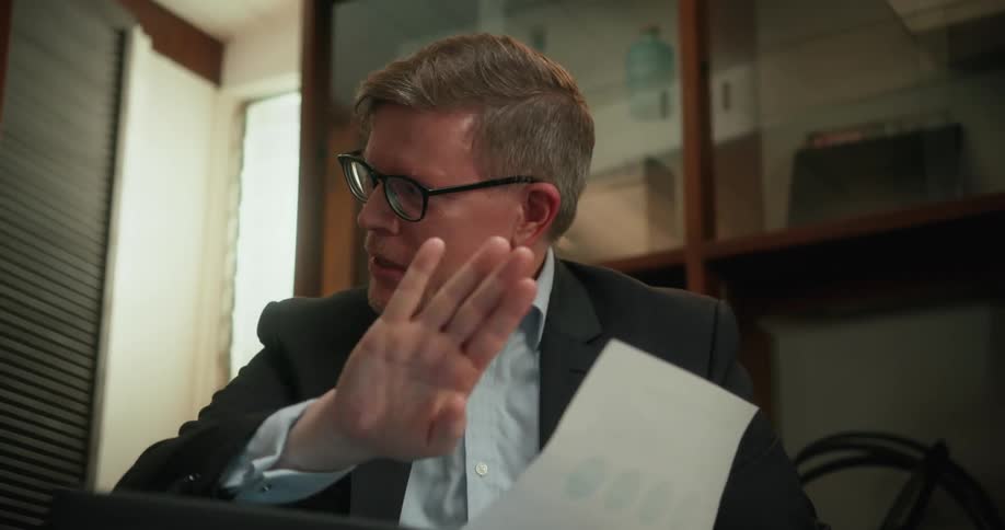 A man discusses information on a piece of paper while sitting in an office