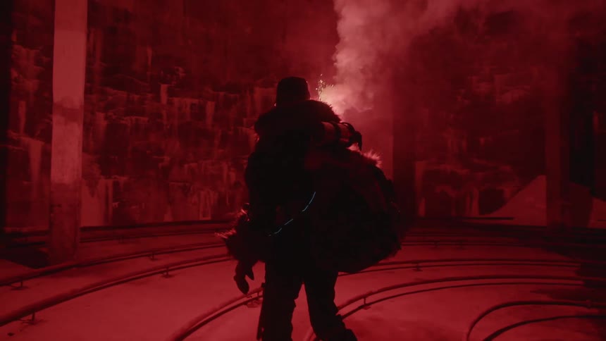 Silhouette of a person wearing a big backpack and carrying a bright red flare in a dark empty building