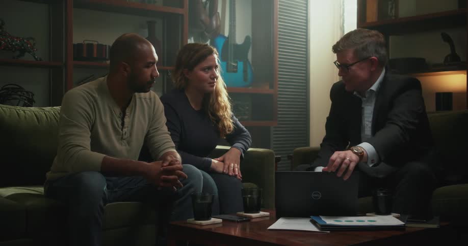 Businessman opens laptop while talking to clients in their home