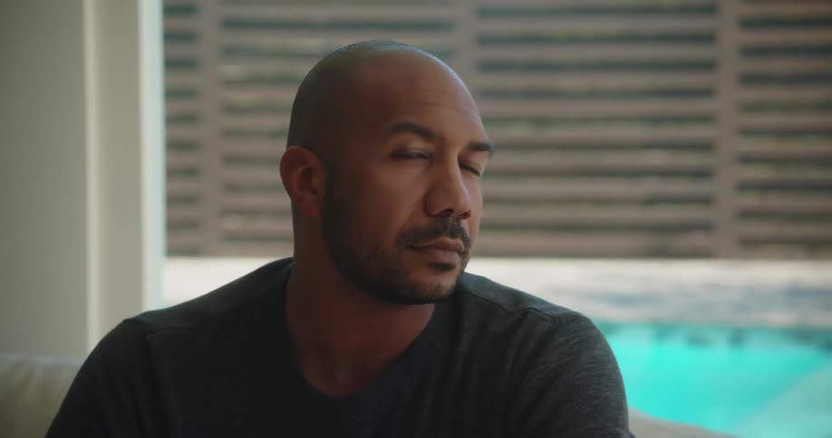 Bald man with beard and gray sweatshirt looks and smirks at camera