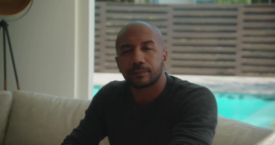 A black male sitting on the couch drinking from a glass