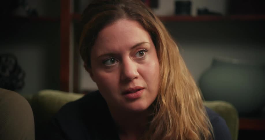 A woman nods while listening to another man talk