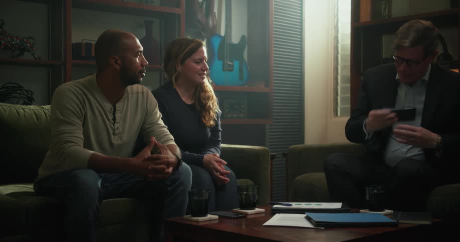 Couple sit down with man in business suit to hold a discussion