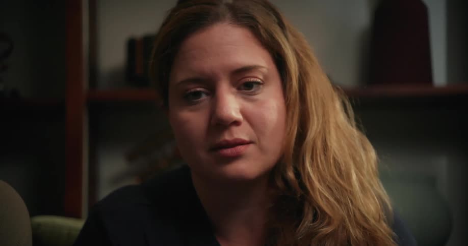 Worried woman with brown wavy hair looks at man in the living room