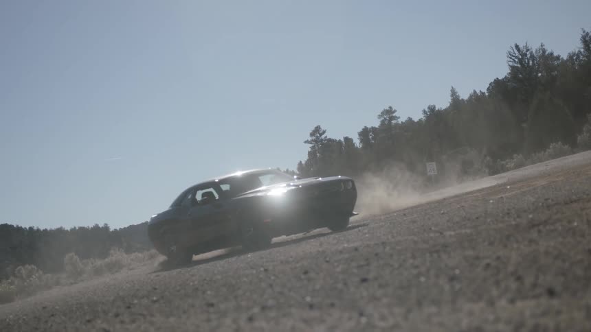 A car spins on a dusty lot