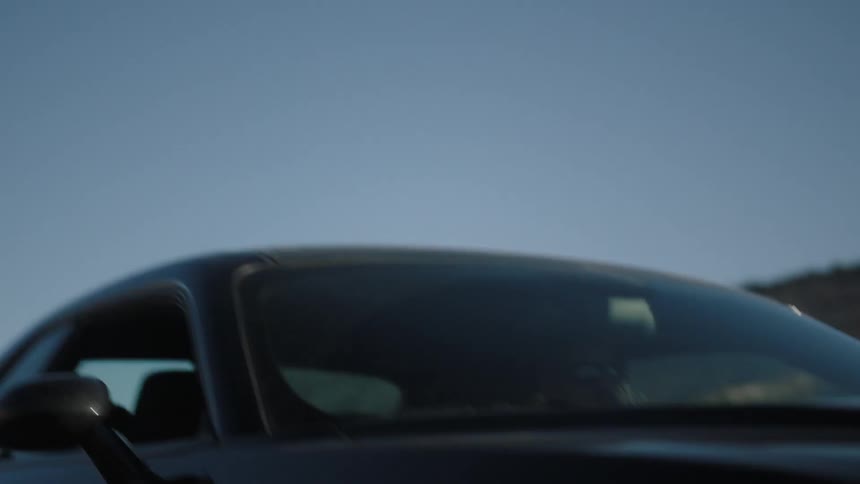A black car drives down a desert road