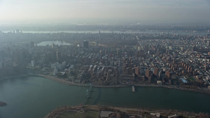 Approaching aerial footage of urban neighborhoods public housing famous landmarks like Central Park and Upper East Side and riverfronts in New York City during winter