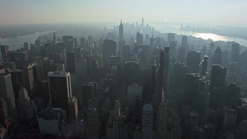 Fly over the hazy skyline of Manhattan to approach the iconic Empire State Building during a winter day