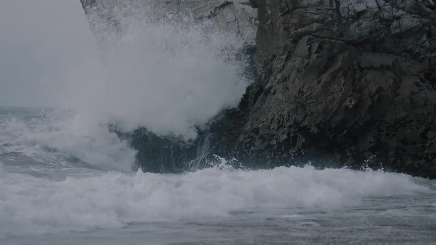 Waves crash onto a large rock