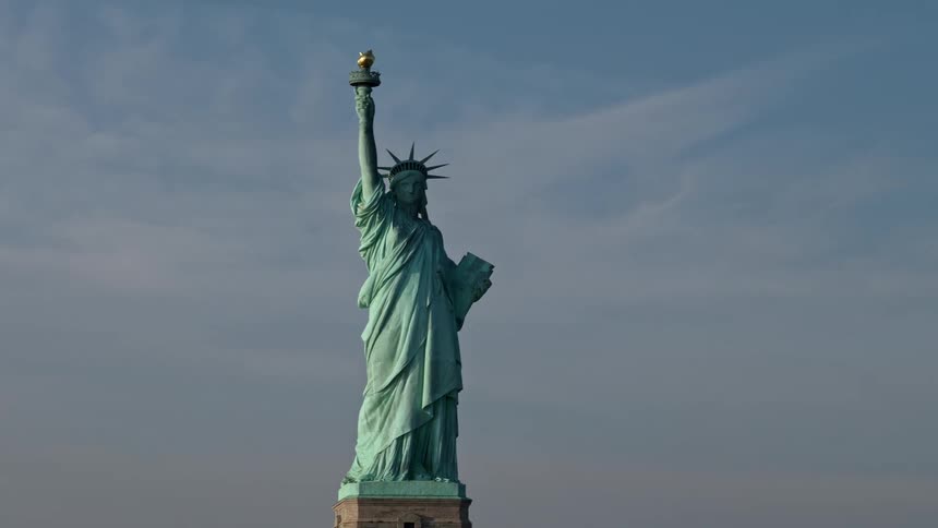A breathtaking aerial view of the Statue of Liberty orbiting over a sunny New York city during winter