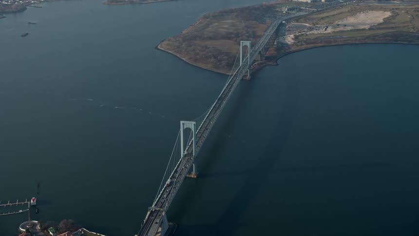 Aerial footage of the Bronx Whitestone Bridge crossing the East River in Long Island New York during winter showing light traffic and a hazy atmosphere