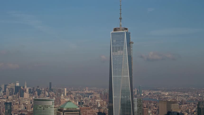 Aerial shot of the iconic Freedom Tower spire in Lower Manhattan New York City as the camera tilts up from the winter landscape below