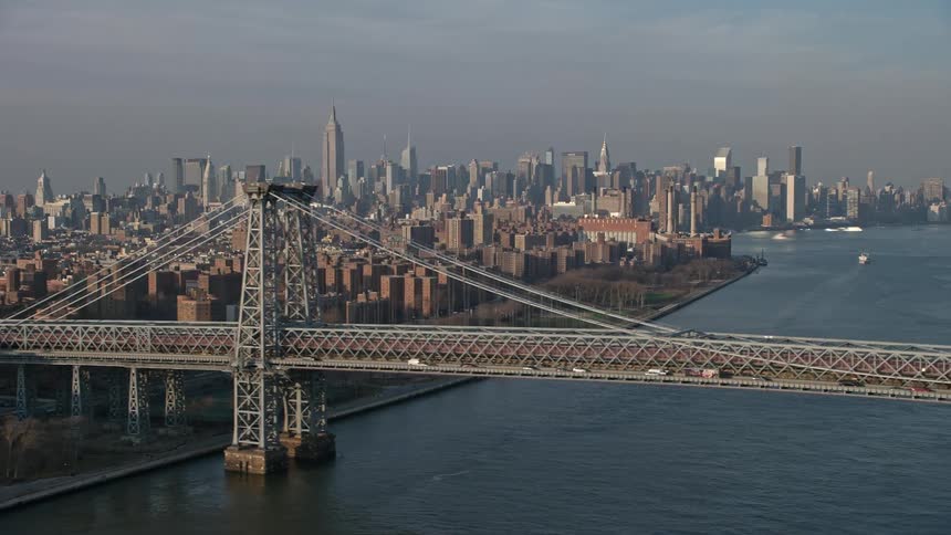 Aerial view of light traffic on the Williamsburg Bridge with Midtown Manhattan skyline in the background on a sunny day during winter in New York City