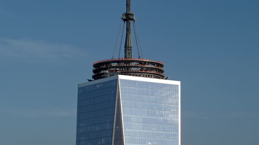 Aerial footage orbiting around the spire and tilting down the Freedom Tower in Lower Manhattan New York City during winter with a hazy skyline