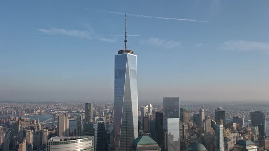 An aerial approach and flyby of One World Trade Center and Lower Manhattan skyscrapers showcasing the iconic structures and downtown areas of New York City during wintertime without snow