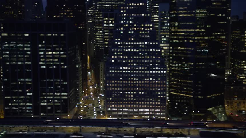 Aerial view of Lower Manhattan New York City during winter night with tall skyscrapers and FDR Drive surrounded by clear skies and light traffic
